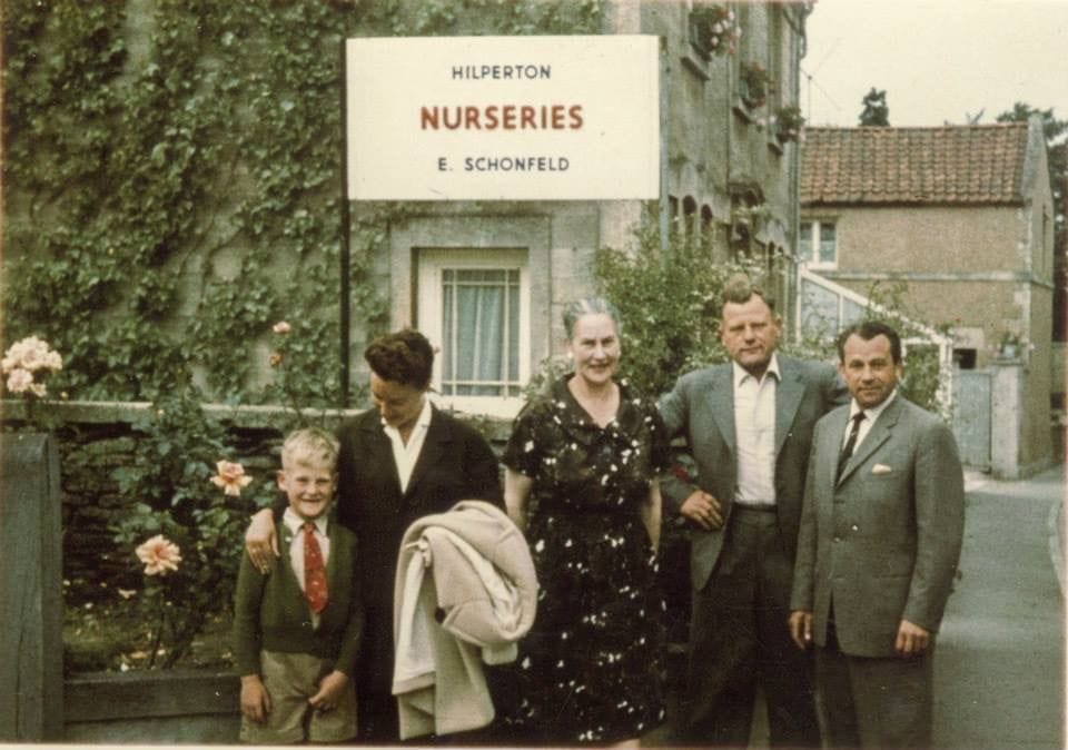 A family group photographed beside the painted sign reading 'Hilperton Nurseries, E. Schönfeld'.