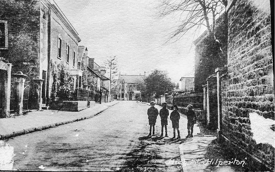 A group of children standing in the road between high boundary walls. Nobody in this photograph has yet been named.